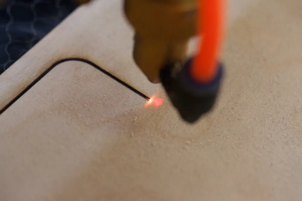 Laser making a cut in a piece of plywood